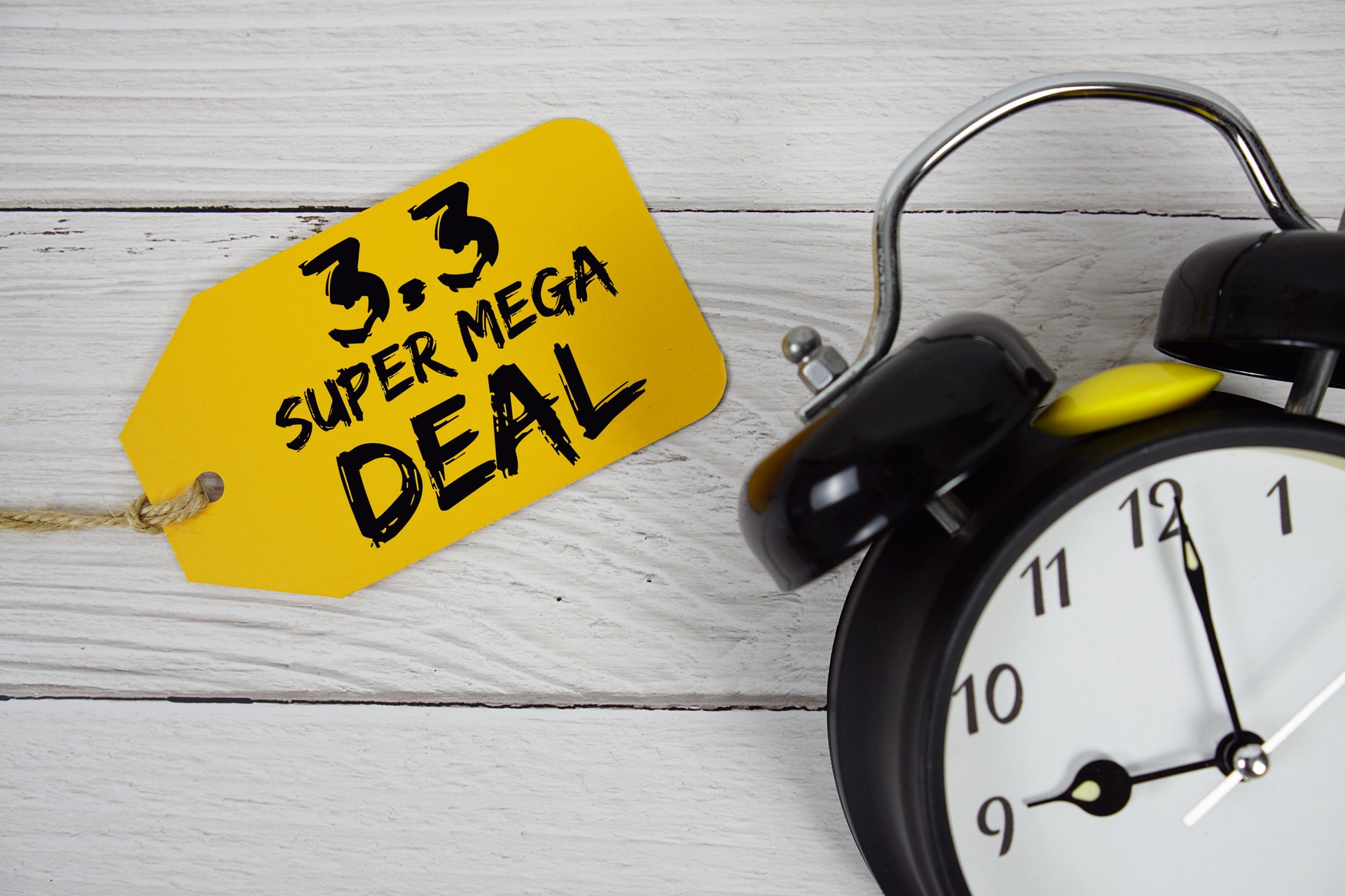 3.3 Super Mega Deals Promotion on price tag with alarm clock on wooden background